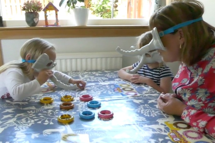 Children play a tabletop game with their childminder.